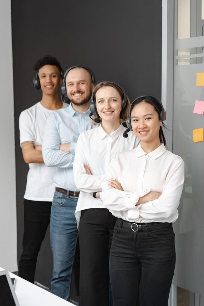 Friendly customer support team with headphones standing in office.